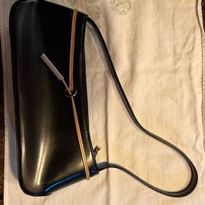 Kaela mini bag with strap. Deep black with tan trim and metal accent.